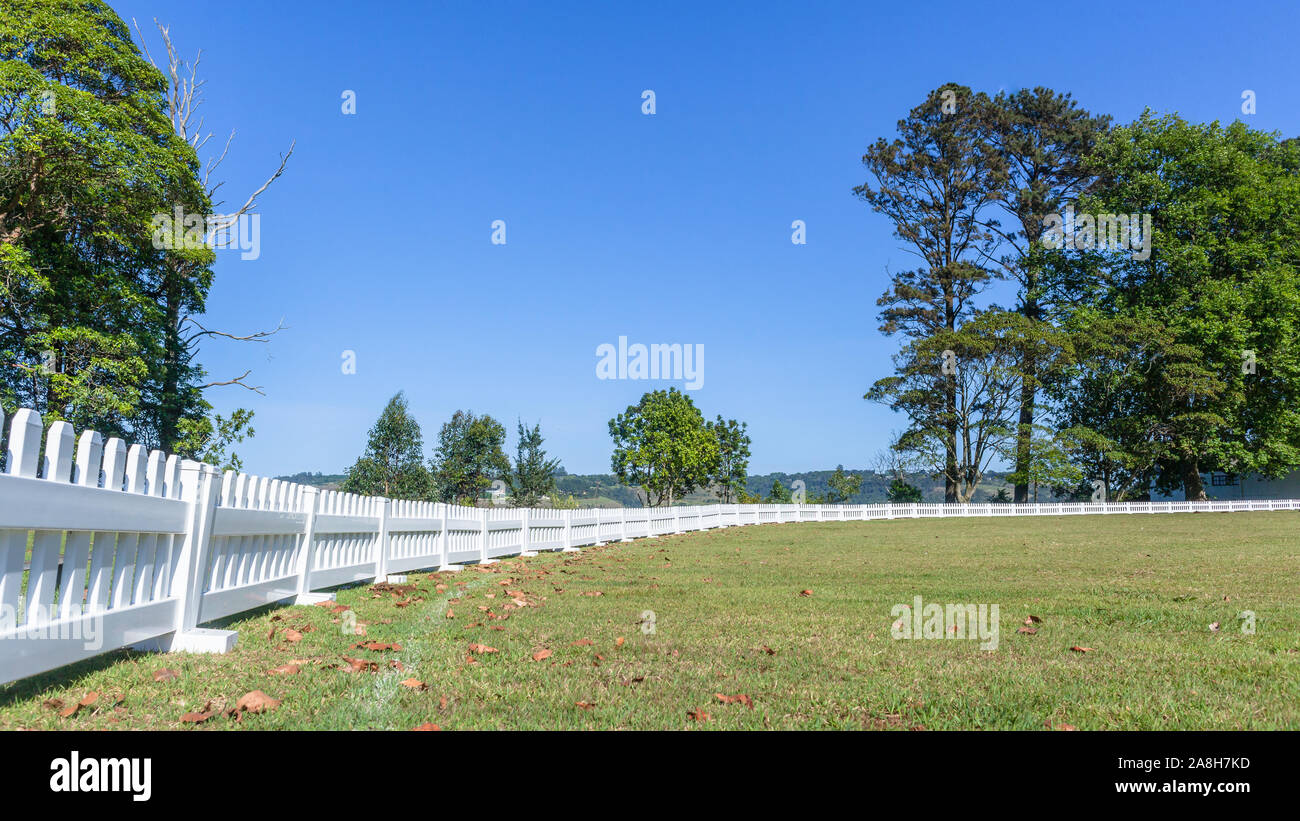 Scenic cricket grounds from white boundary fence of grass field astro and grass pitch morning  summer blue day countryside landscape. Stock Photo
