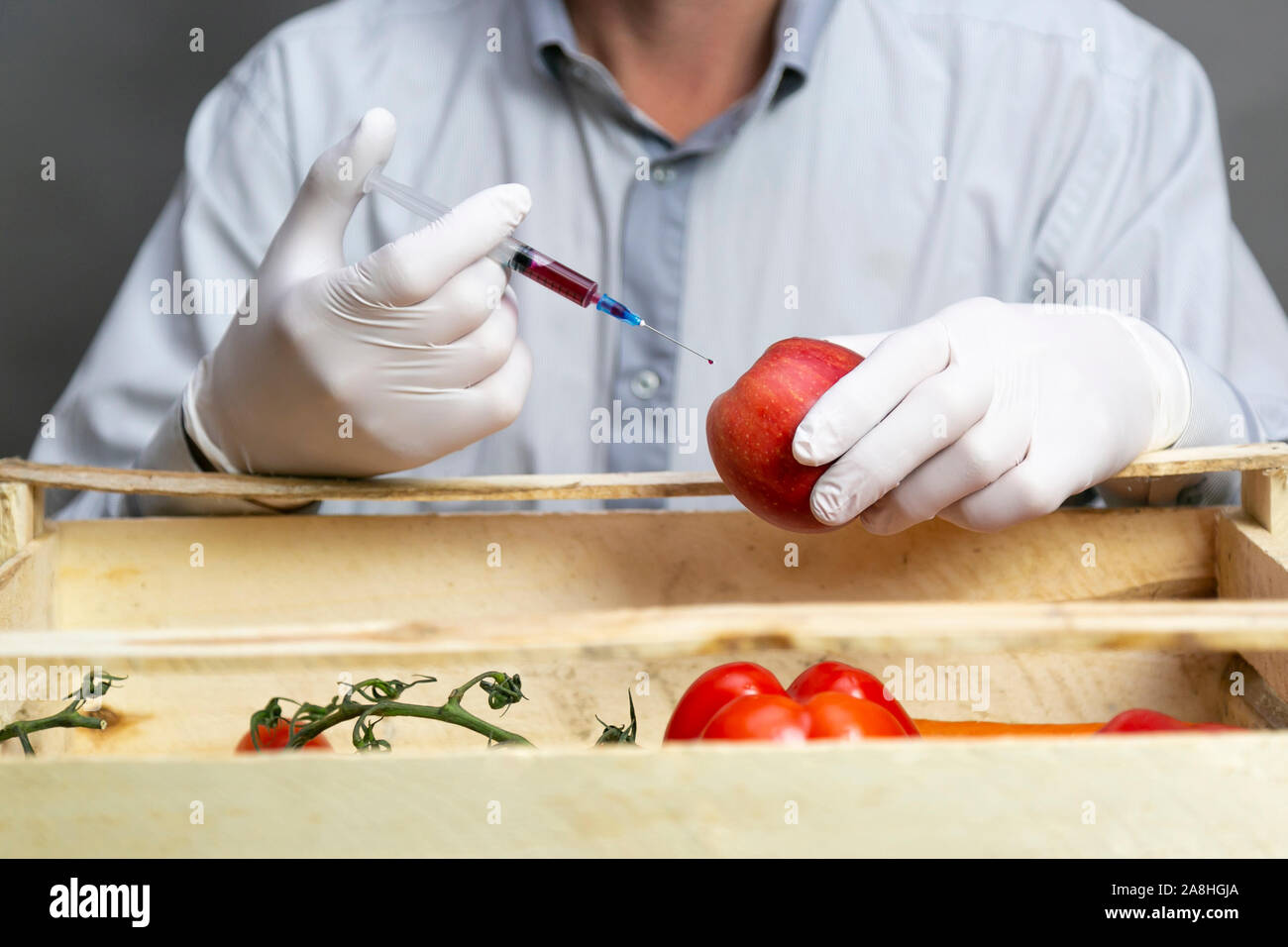 A man injects chemicals into an orange, pesticides and fertilizers and chemicals with a syringe to increase the shelf life of the fruit Stock Photo
