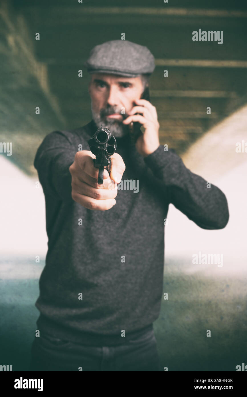 Man holding a gun and talking on the phone Stock Photo