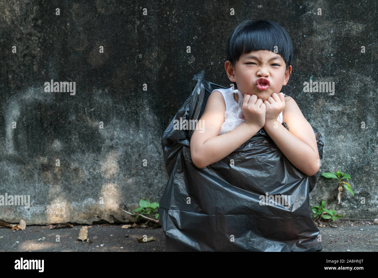 Little girl is acting in garbage bag. Stock Photo