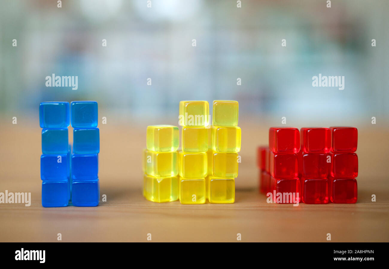 Stacked colorful cubes. Comparison, illustration, building blocks, yellow, blue, red. Stock Photo