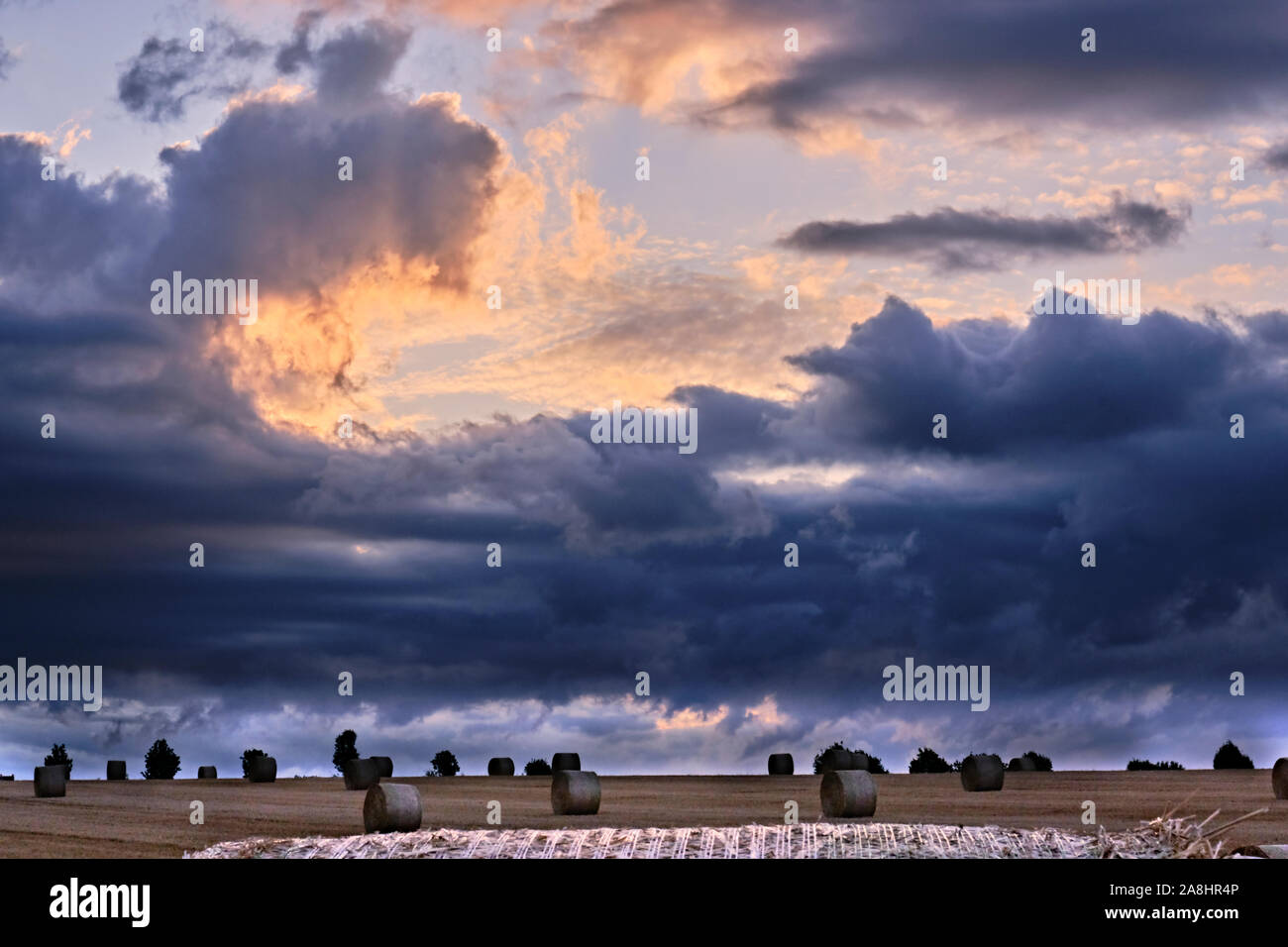 Storm clouds gathering on the horizon over bales of hay Stock Photo