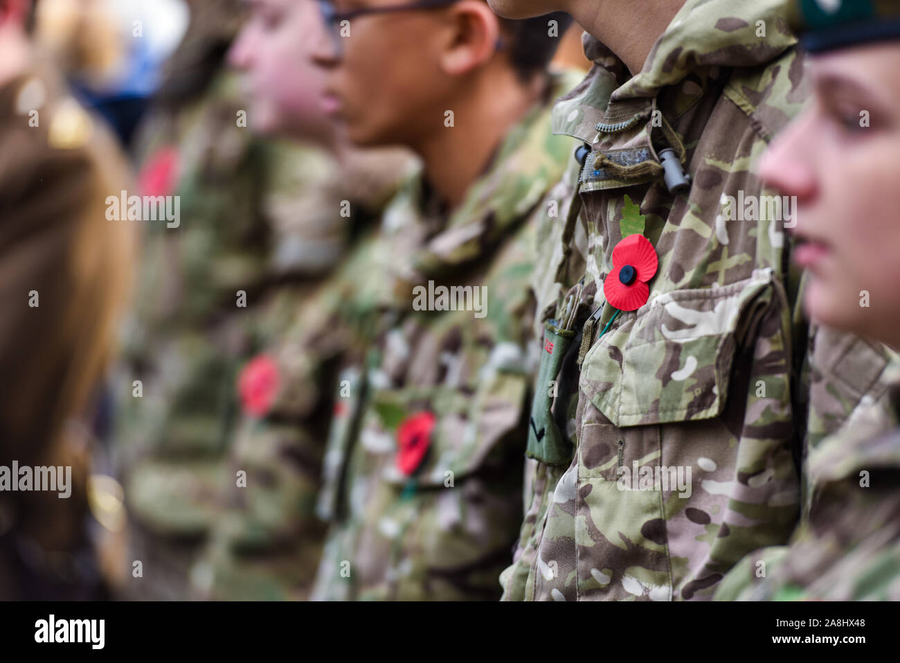Army cadets stand in front of the war memorial wearing their poppies