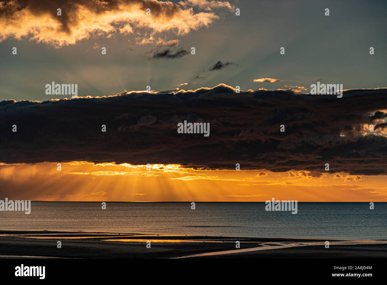 Sunbeams at sunset over the sea at Rhyl, North Wales Stock Photo