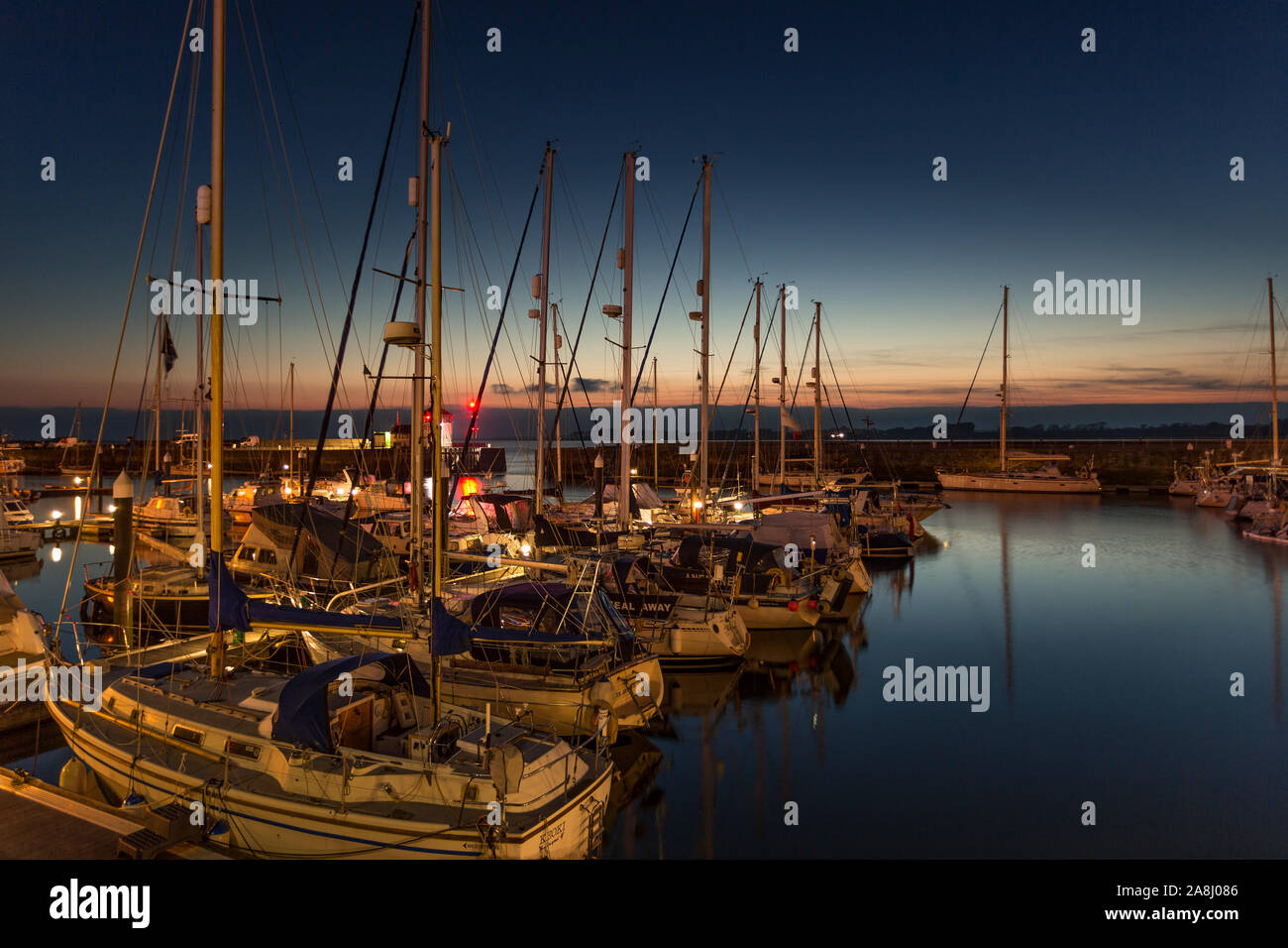 Yachts moored in the Victoria Dock at Caernarfon at dusk on the North Wales coast Stock Photo