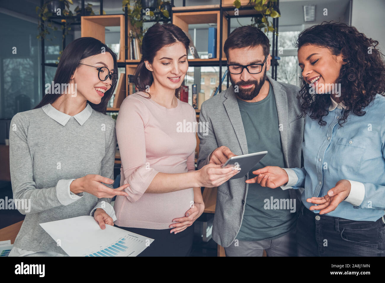 Startupers working together at office standing browsing internet on digital tablet joyful Stock Photo