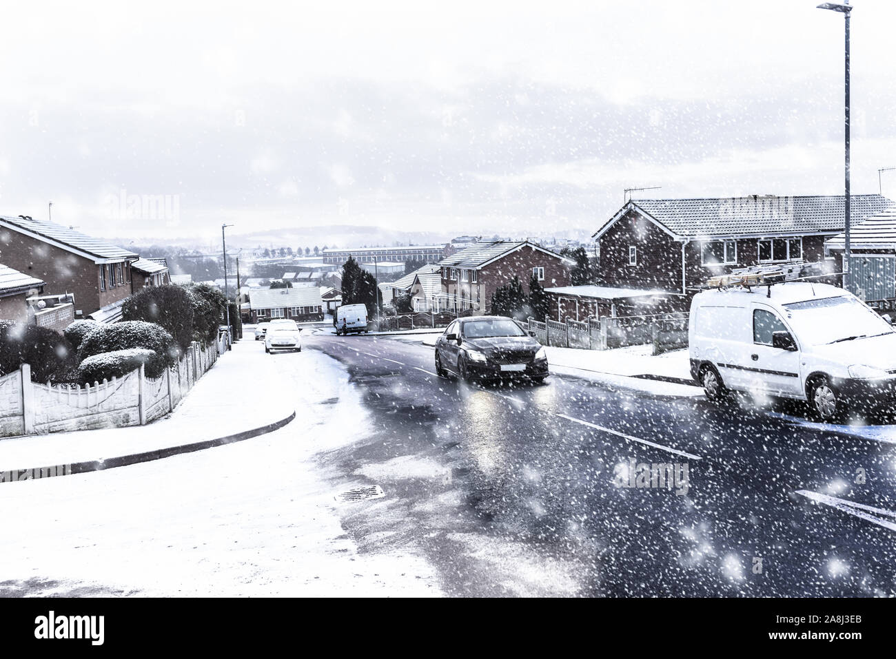 Snow covered cars, recycling bins, roads and houses at night in Longton