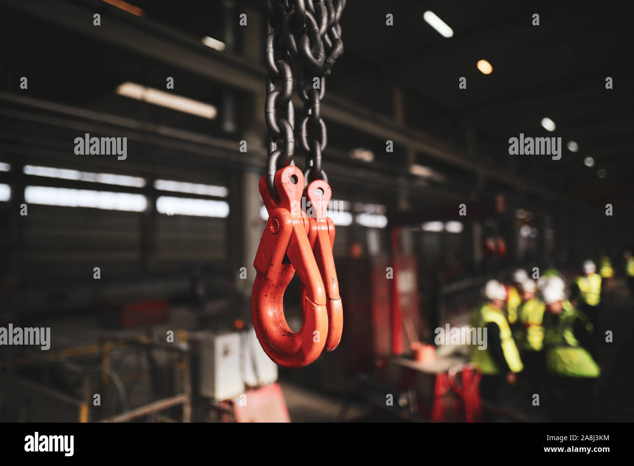 Shallow depth of field (selective focus) image with red industrial crane lifting hooks inside a factory. Stock Photo