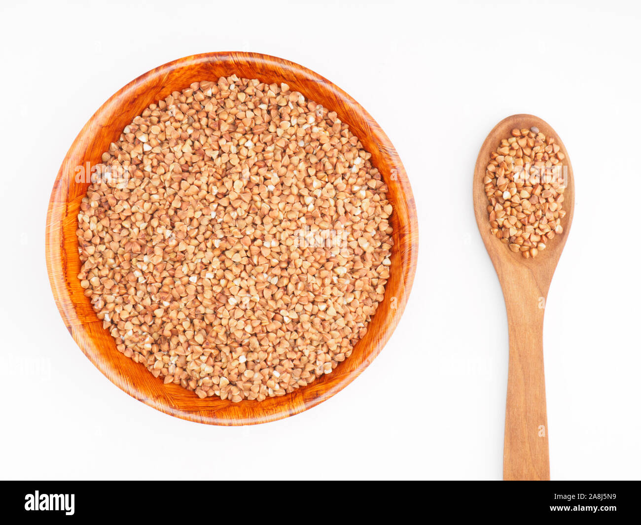 Buckwheat groats in bamboo bowl and in wooden spoon on white background