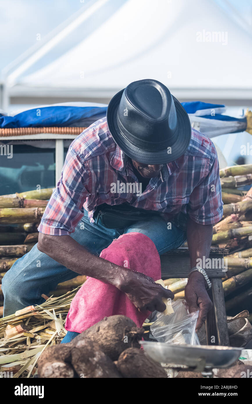Marie-Galante island in  Guadeloupe, man who peels some sugar cane on the market Stock Photo