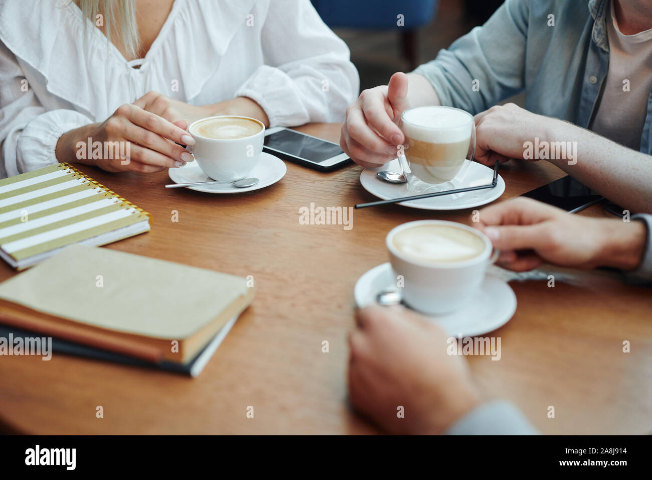 Hands of college friends gathered by table in cafe after classes for a drink Stock Photo