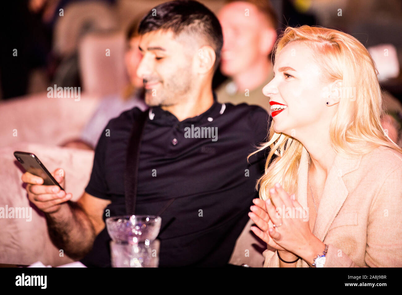 Young dark hair man and blond woman enjoy White Collars Boxing league amature boxing fight night at ringside in one of Kiev clubs. Stock Photo