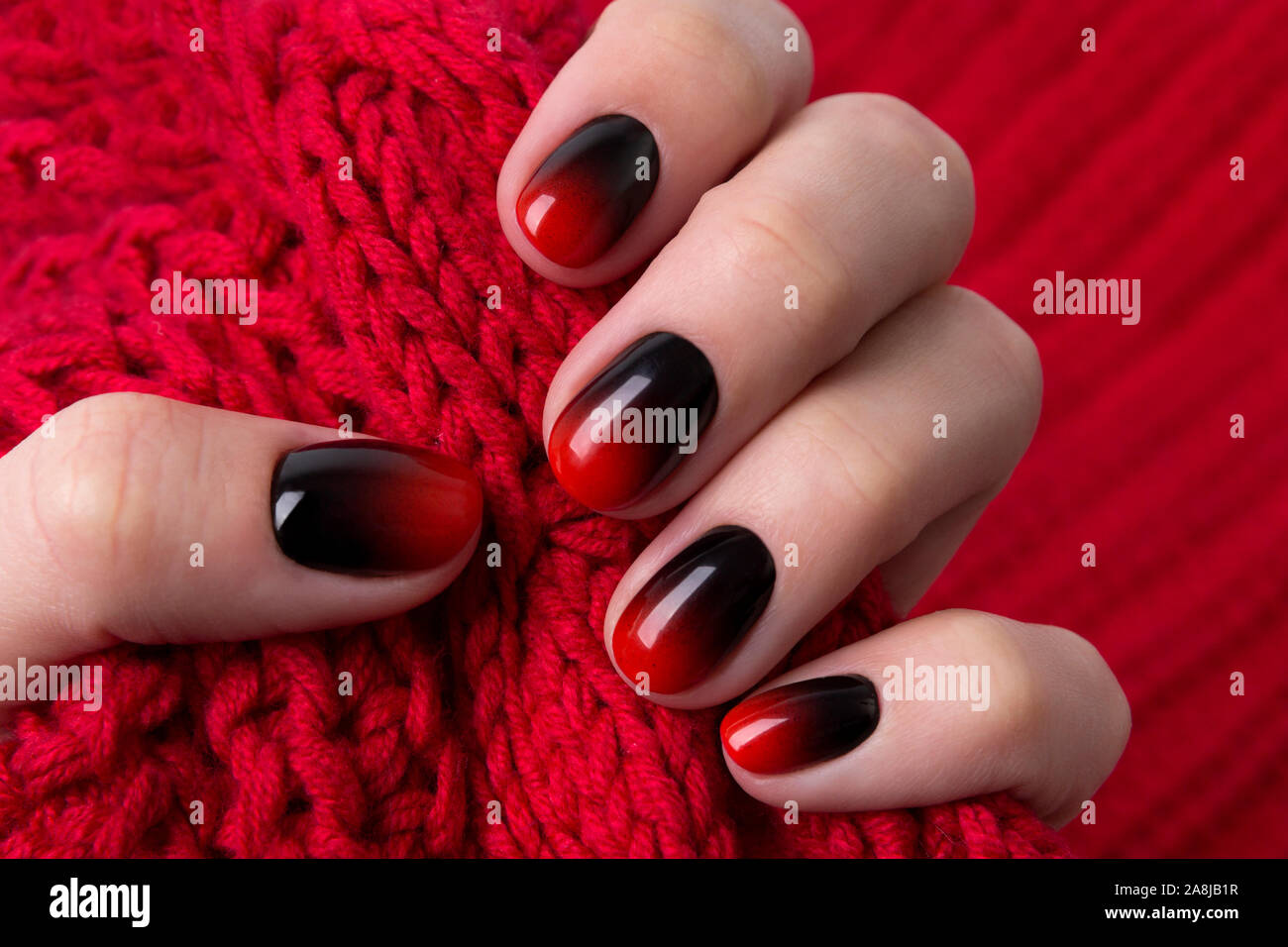 Female hand with red black ombre gradient nails hold wool textile fabric  Stock Photo - Alamy