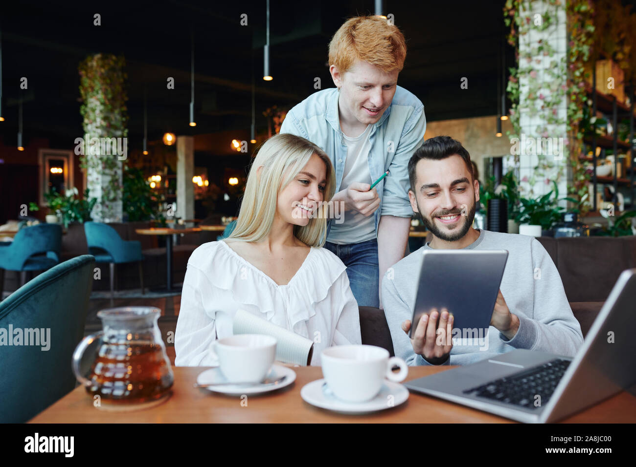 Young students using touchpad and laptop while searching for information Stock Photo