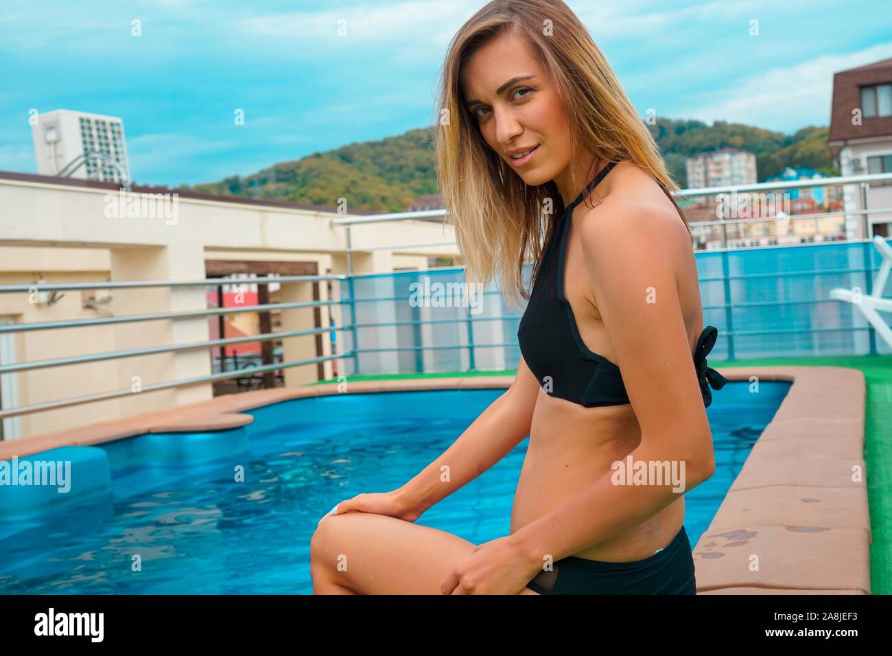 Beautiful tanned woman sitting near swimming pool Stock Photo