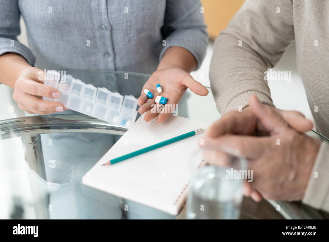 Hands of young woman holding pills while showing medicine to sick senior father Stock Photo