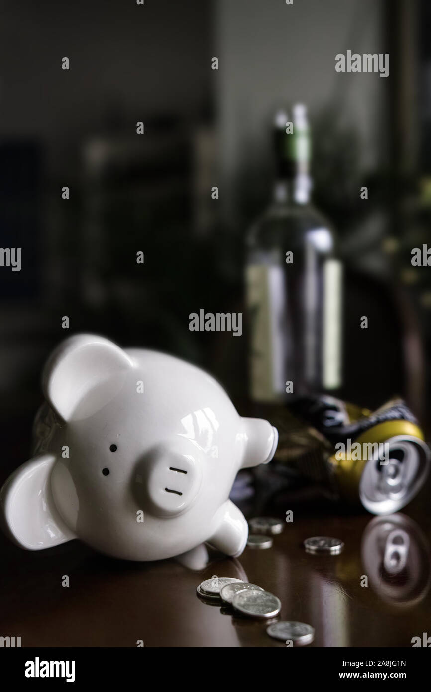 Opened, emptied, and toppled piggy bank, coins and alcoholism.. Stock Photo