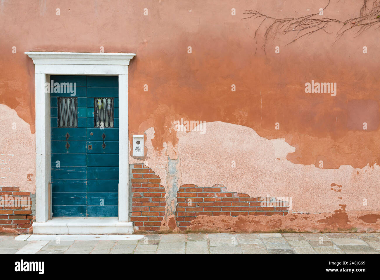 Vintage front door painted blue and a wall with old weathered render in Venice, Italy Stock Photo