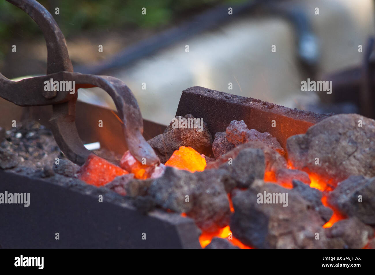 blacksmith furnace with burning coals, tools, and glowing hot metal workpieces, close-up Stock Photo