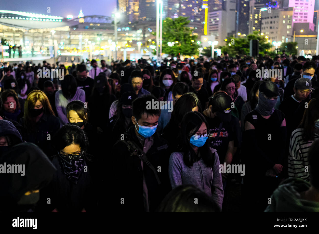 Masked demonstrators praying during the rally.Memorial rally at Tamar Park in Hong Kong to mourn the death of a 22 years old university student, Alex Chow Tsz Lok who died from a serious brain injury during a fall on November 4th as police skirmished with demonstrators last weekend. He was left in critical condition and died after suffering a cardiac arrest. Stock Photo