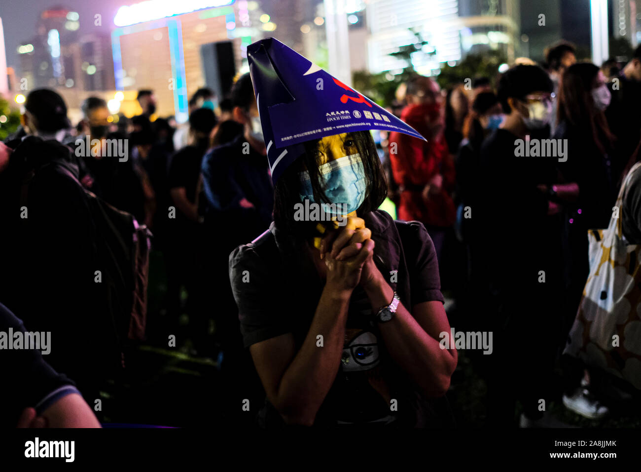 A man with a mask prays during the rally.Memorial rally at Tamar Park in Hong Kong to mourn the death of a 22 years old university student, Alex Chow Tsz Lok who died from a serious brain injury during a fall on November 4th as police skirmished with demonstrators last weekend. He was left in critical condition and died after suffering a cardiac arrest. Stock Photo