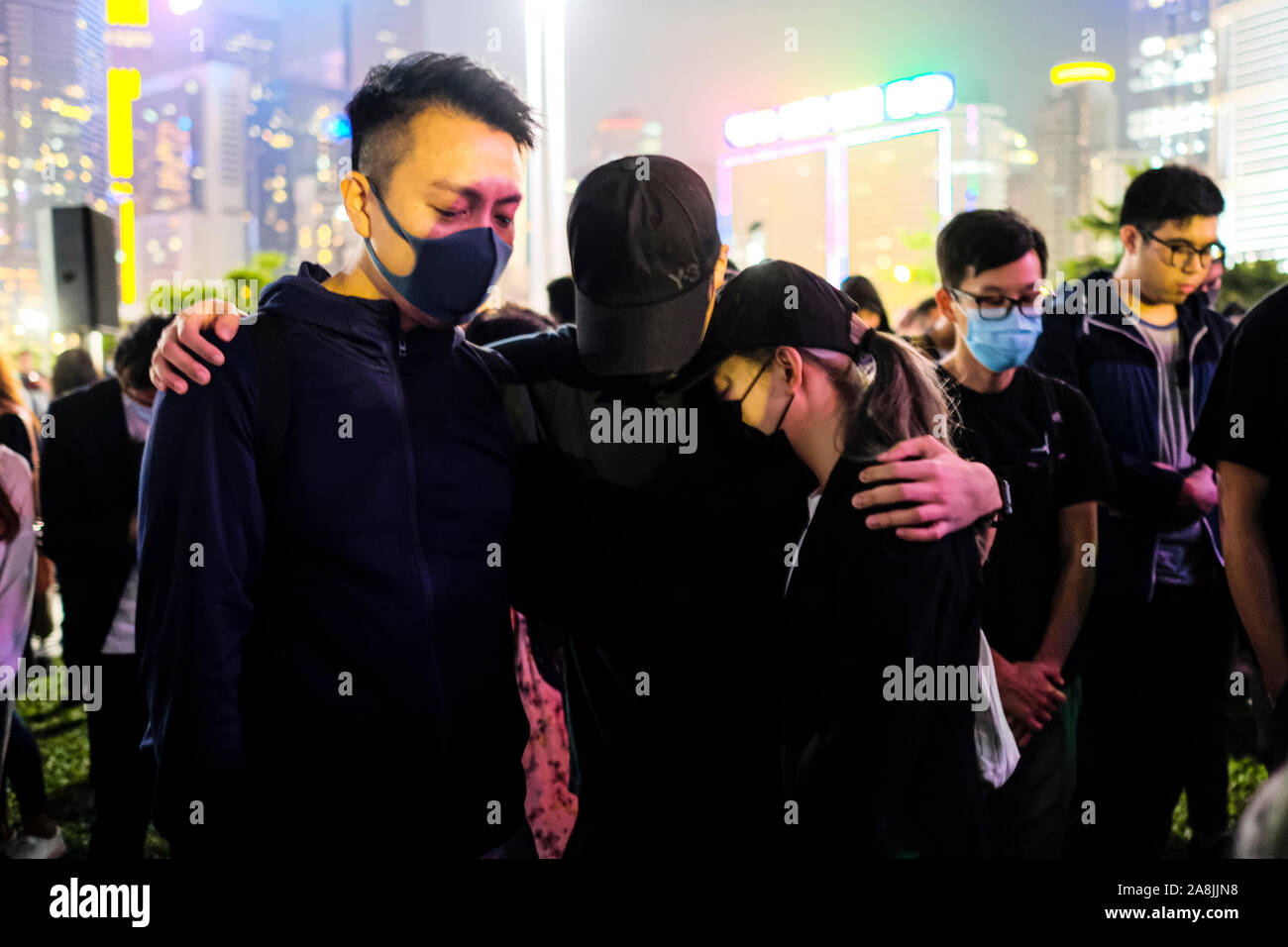 Demonstrators hug each other during the rally.Memorial rally at Tamar Park in Hong Kong to mourn the death of a 22 years old university student, Alex Chow Tsz Lok who died from a serious brain injury during a fall on November 4th as police skirmished with demonstrators last weekend. He was left in critical condition and died after suffering a cardiac arrest. Stock Photo