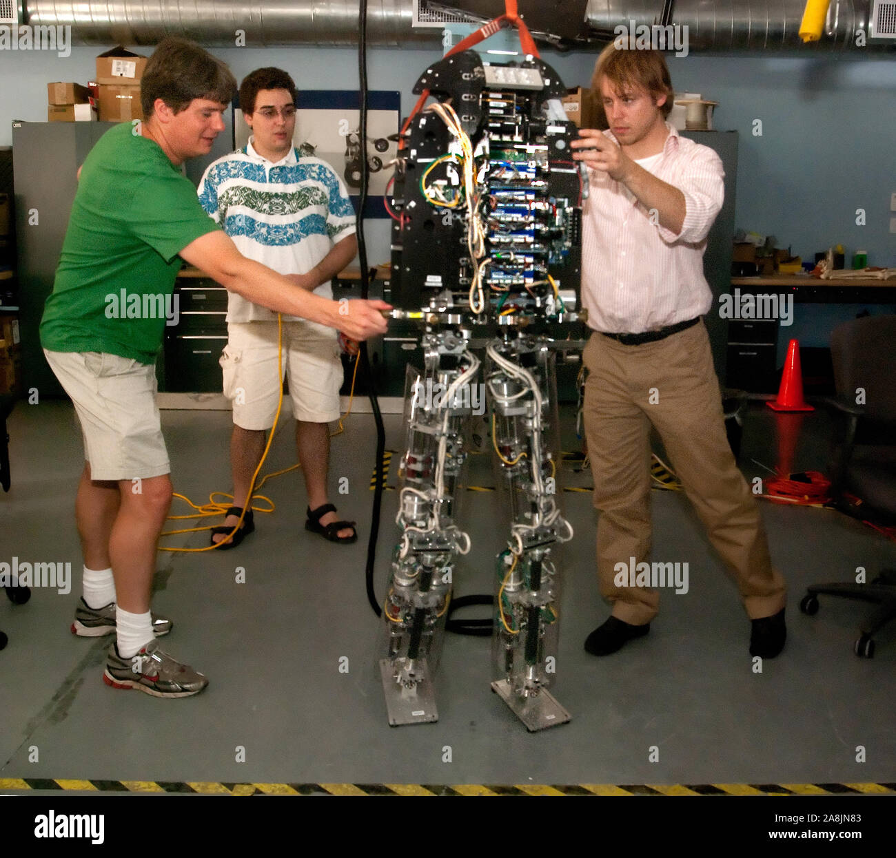 Research scientist Jerry Pratt and associates take turns shoving M2V2, a bipedal robot, at the Institute for Human and Machine Cognition in Pensacola. Stock Photo