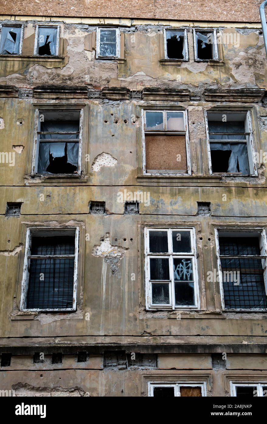 Old Desolate Apartment House With Damaged Facade And Bursted Windows Stock Photo