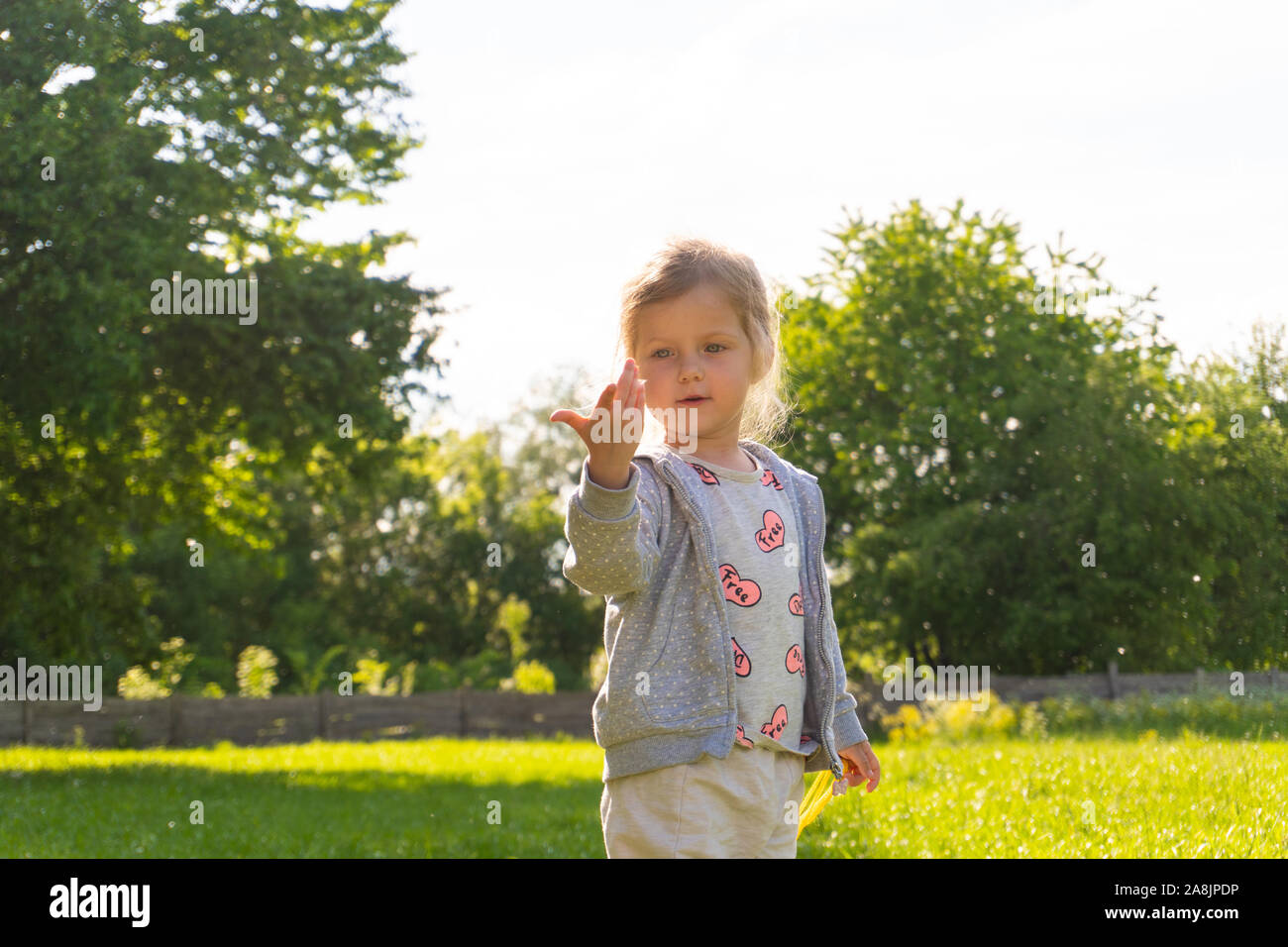 Little girl playing with fure from trees in the park Stock Photo