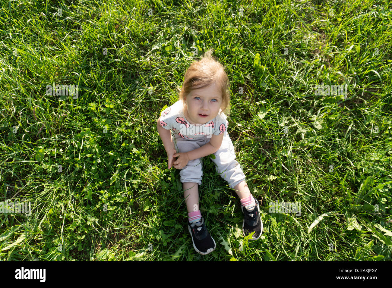 Little girl sitting on the grass at the lawn Stock Photo Alamy