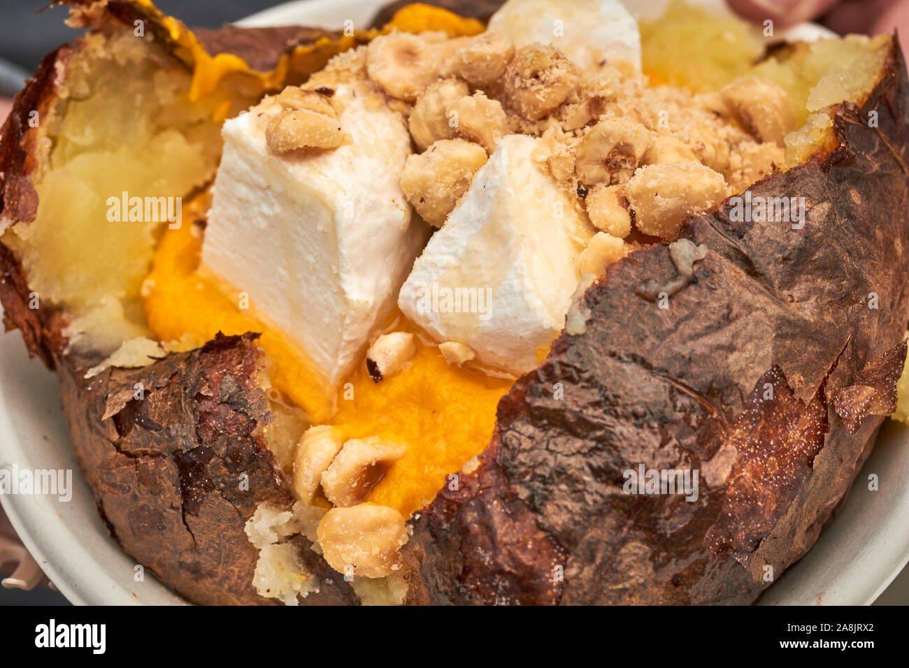 A Piemontese stuffed, baked potato. Italian/British fusion with a jacket potato, zucca, cheese, and hazelnuts. Stock Photo