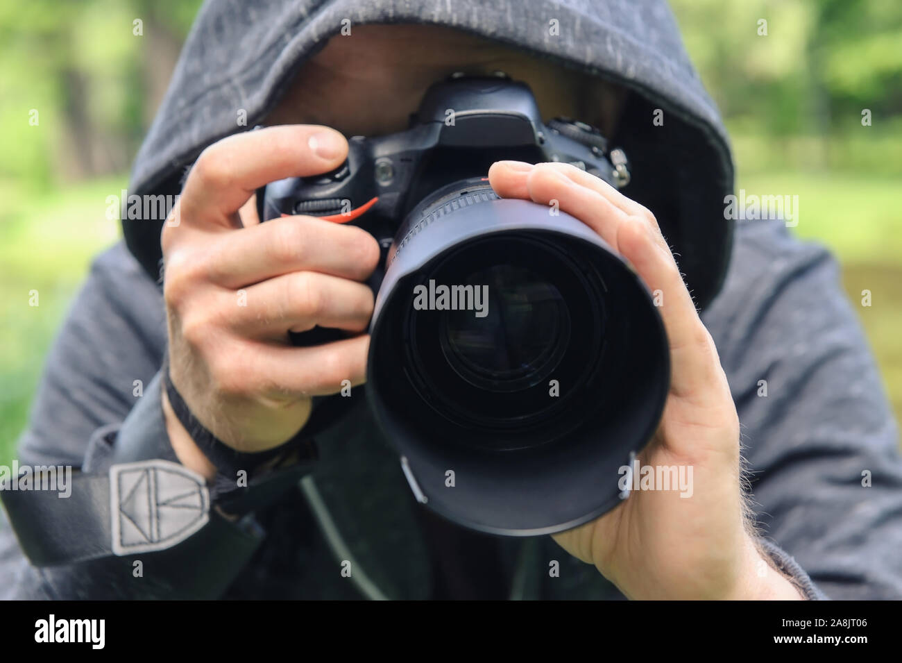 The photographer hidden with the camera. A man in a hood is taking pictures hidden. Stock Photo