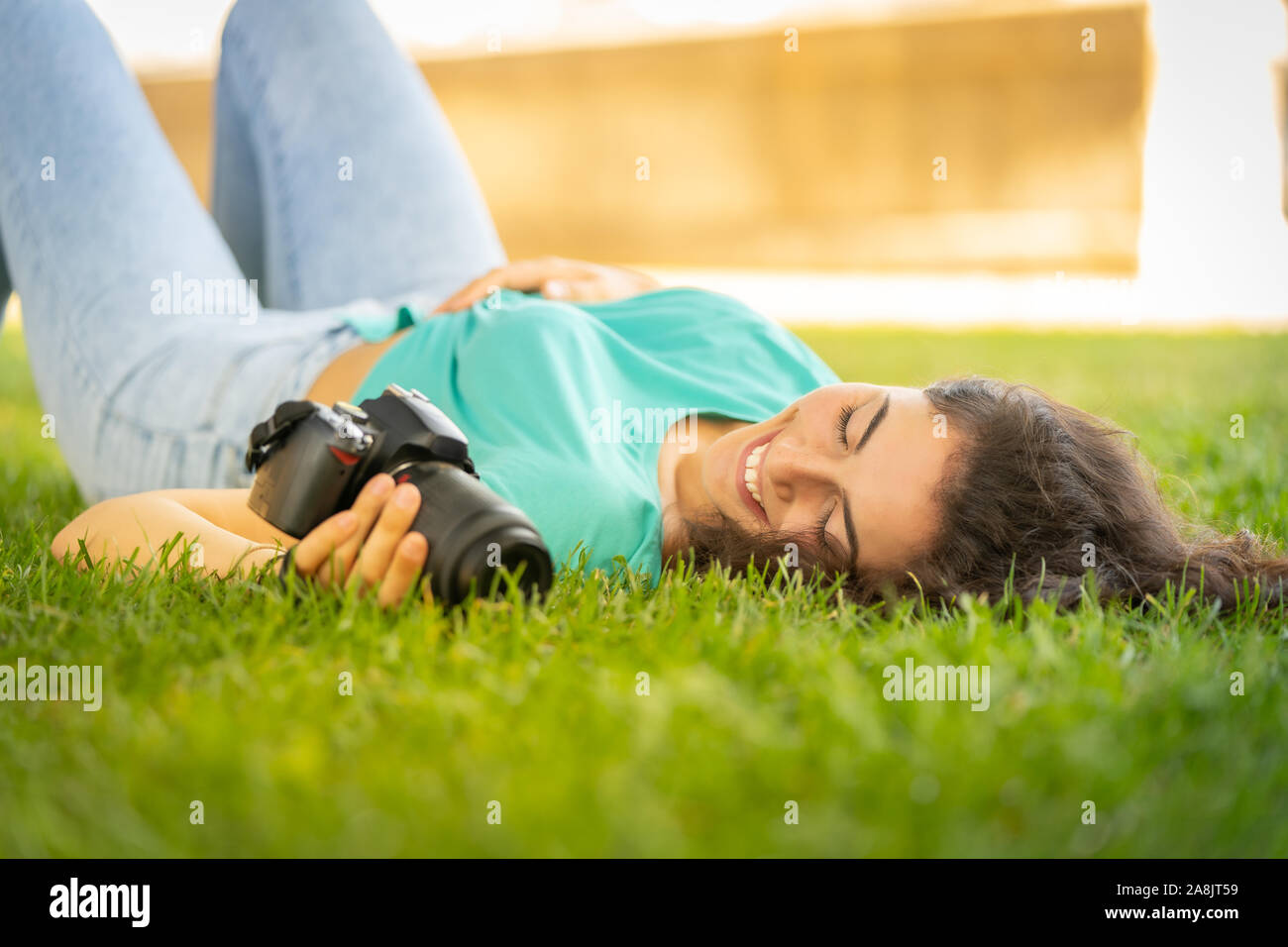 Photographer girl lying on the grass happy and smiling, relaxing Stock Photo