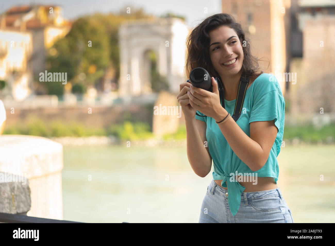 Smiling girl in an Italian city with a camera in her hand. Stock Photo