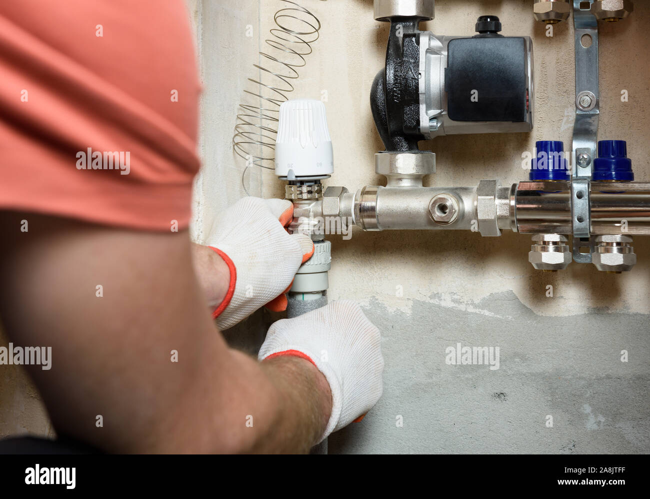 A worker is installing a thermal head on the home heating system distributor. Stock Photo