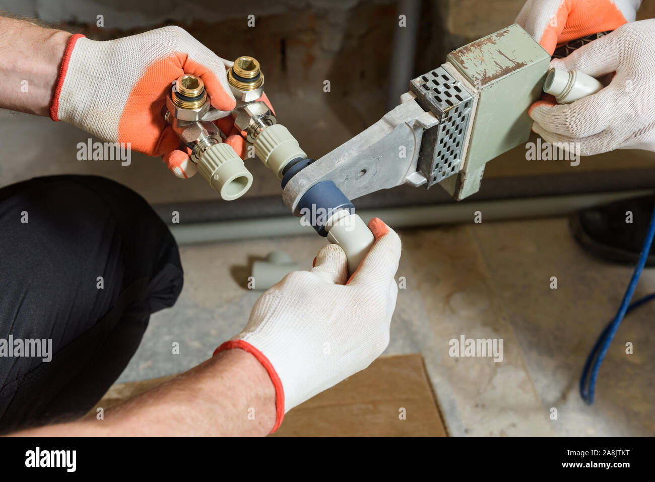 The worker is soldering plastic pipes with HPiece valve for home heating system Stock Photo Alamy
