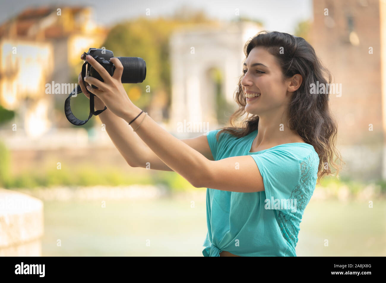 Smiling girl in an Italian city with a camera in her hand. Stock Photo