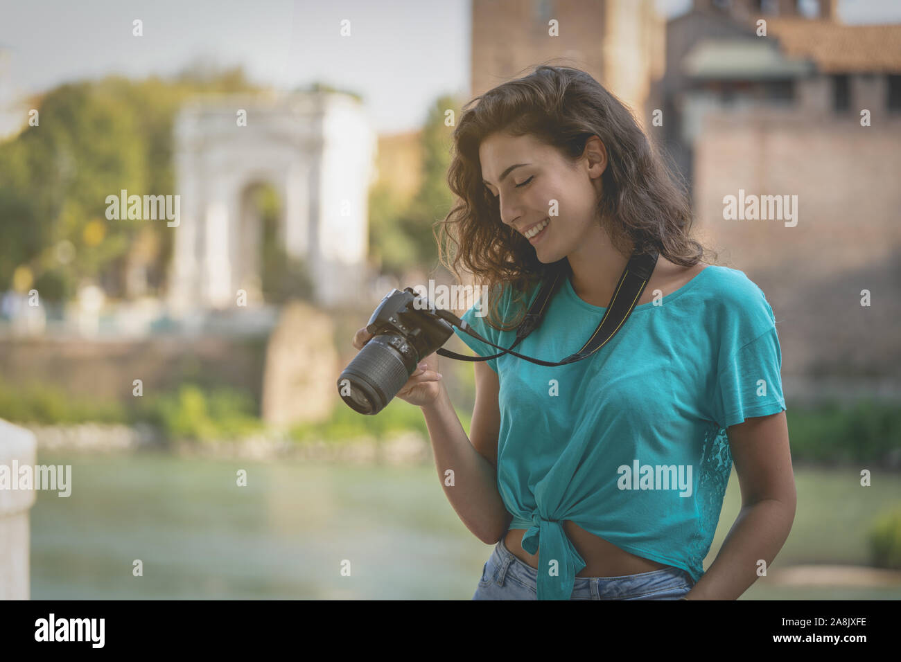 Smiling girl in an Italian city looking at the screen of a camera.  Stock Photo