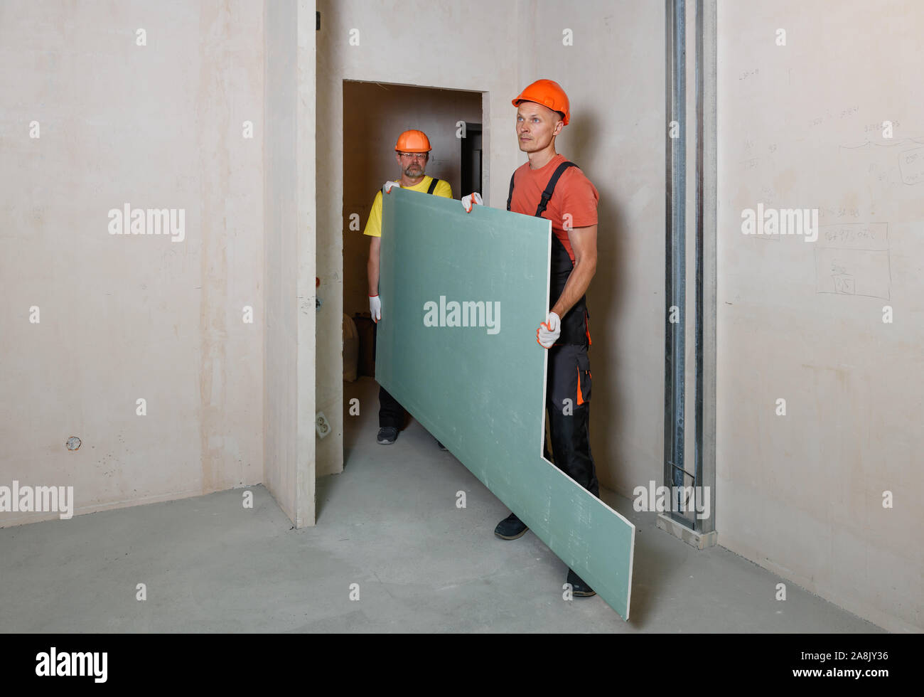 Workers are carrying plasterboard for further attachment to the ceiling. Stock Photo
