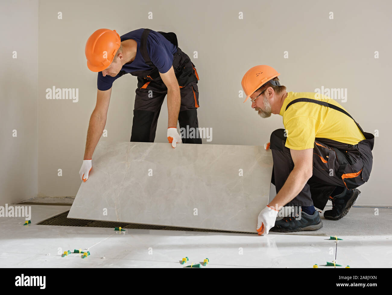 Workers are installing a large ceramic tile on the floor Stock Photo Alamy