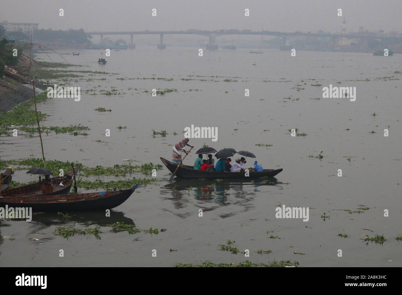 Bangladeshi people cross the River Buriganga during the rainy weather