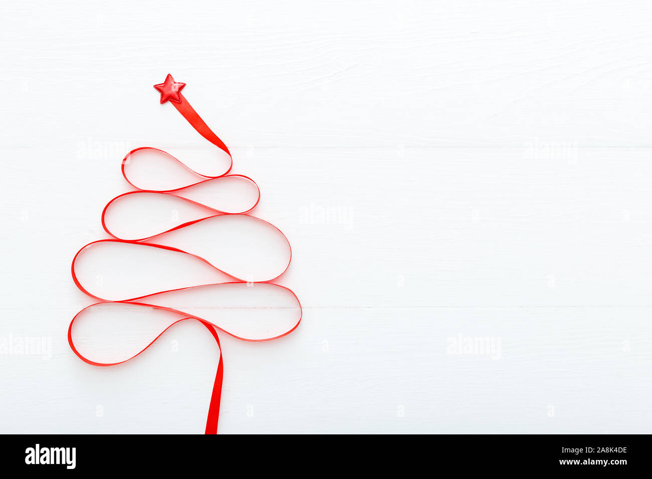 Christmas Tree made from Red satin ribbon with a star on the top on white wooden background. Xmas, winter, new year concept. Flat lay, top view, copy Stock Photo