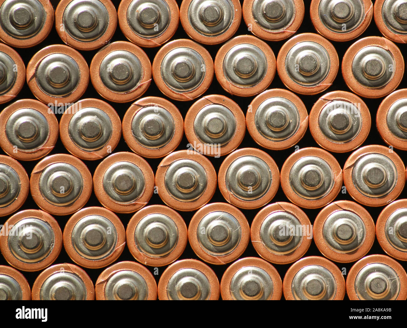 Background wallpaper of columns of batteries positive side up. Multiple batteries stacked together to form an organized vertical pattern. Stock Photo