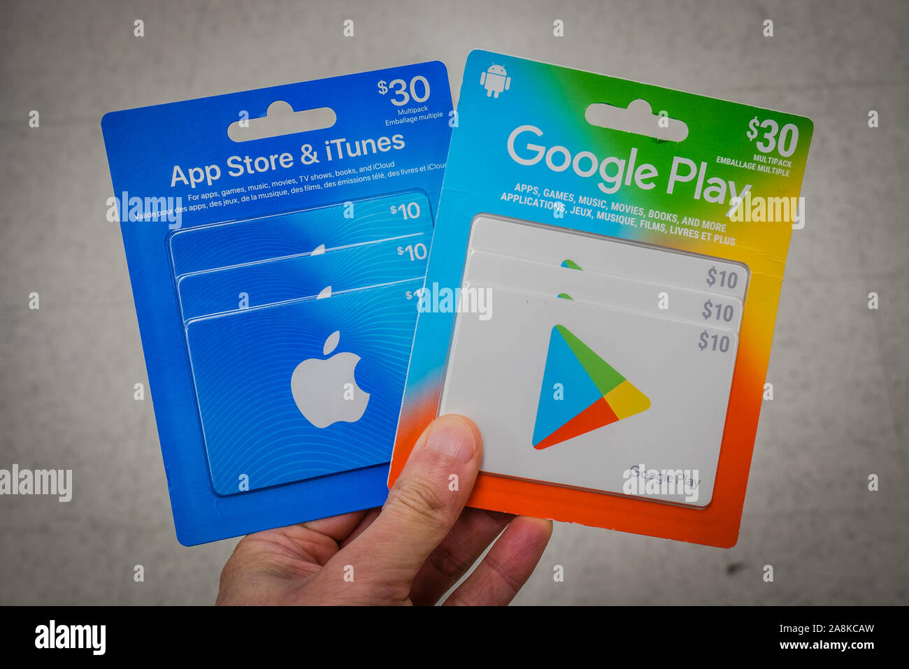 a hand holding apple and google play store gift cards Stock Photo