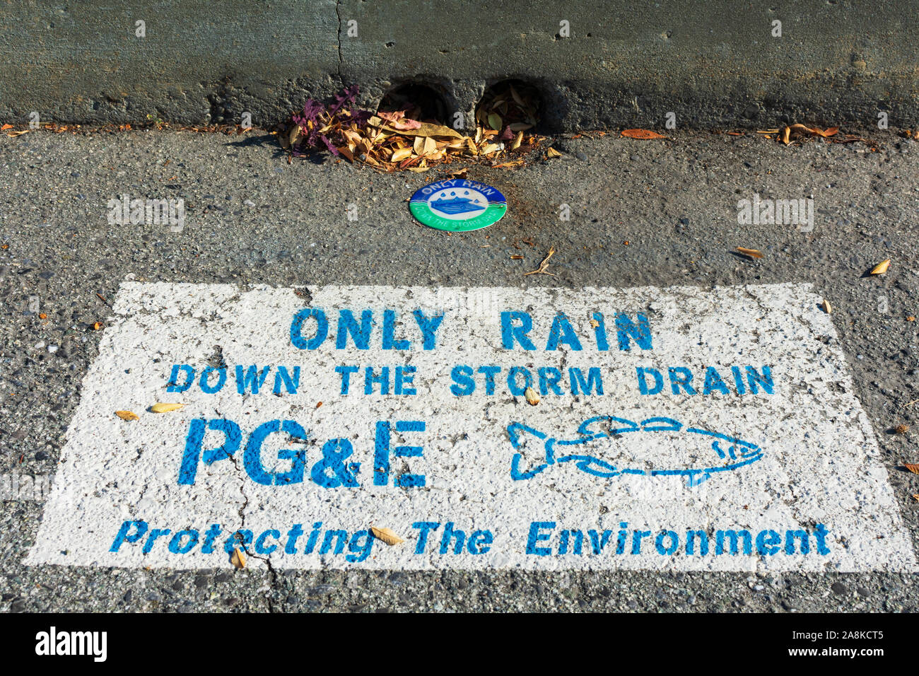 Only rain down to storm drain warning sign PG&E,Pacific Gas and Electric Company, near street drain inlet. Fish Silhouette. Protecting the environment Stock Photo