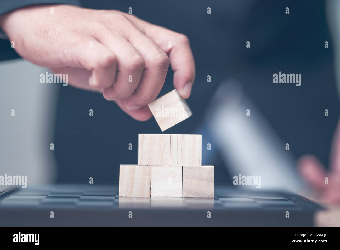hand holding and arranging wood block stacking as step stair with space ...