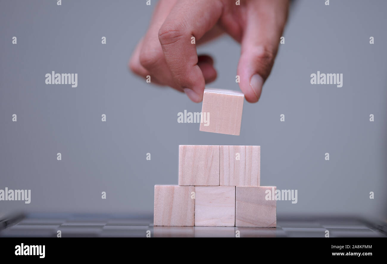 hand holding and arranging wood block stacking as step stair with space ...