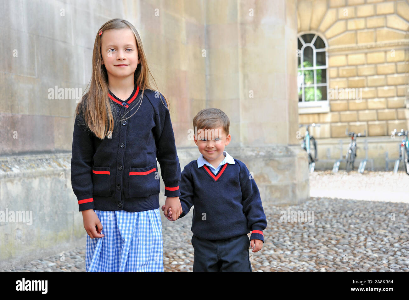 Primary school children ready for school. The younger girl's brother is excited that he finally gets to join his big sister at private school. Stock Photo