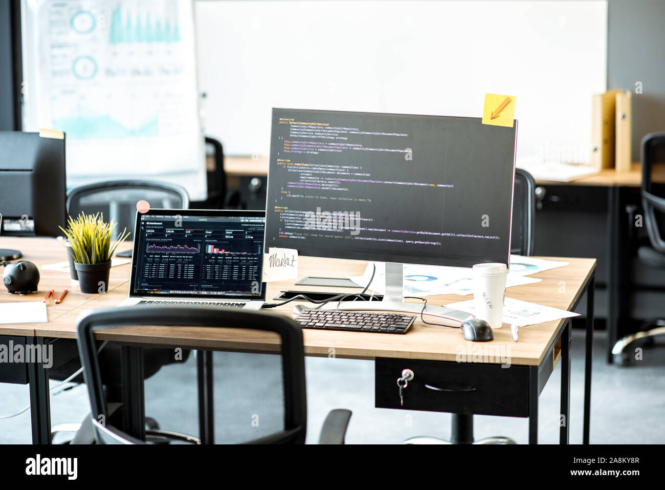 Programmer's working place with computers and programming code on the monitors in the office Stock Photo