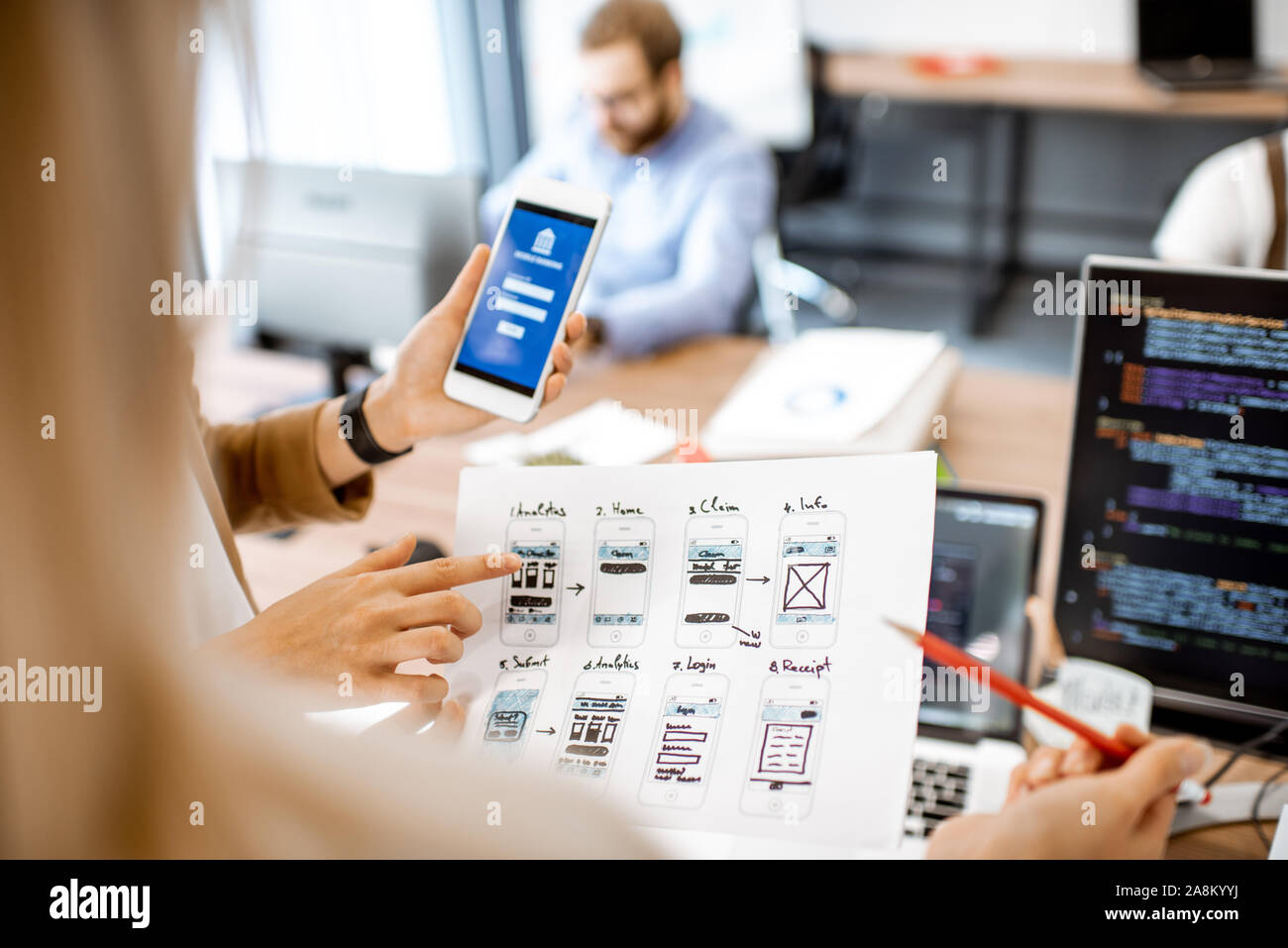 Developers or web designers developing mobile application for banking in the office, close-up on phone and paper sketches Stock Photo